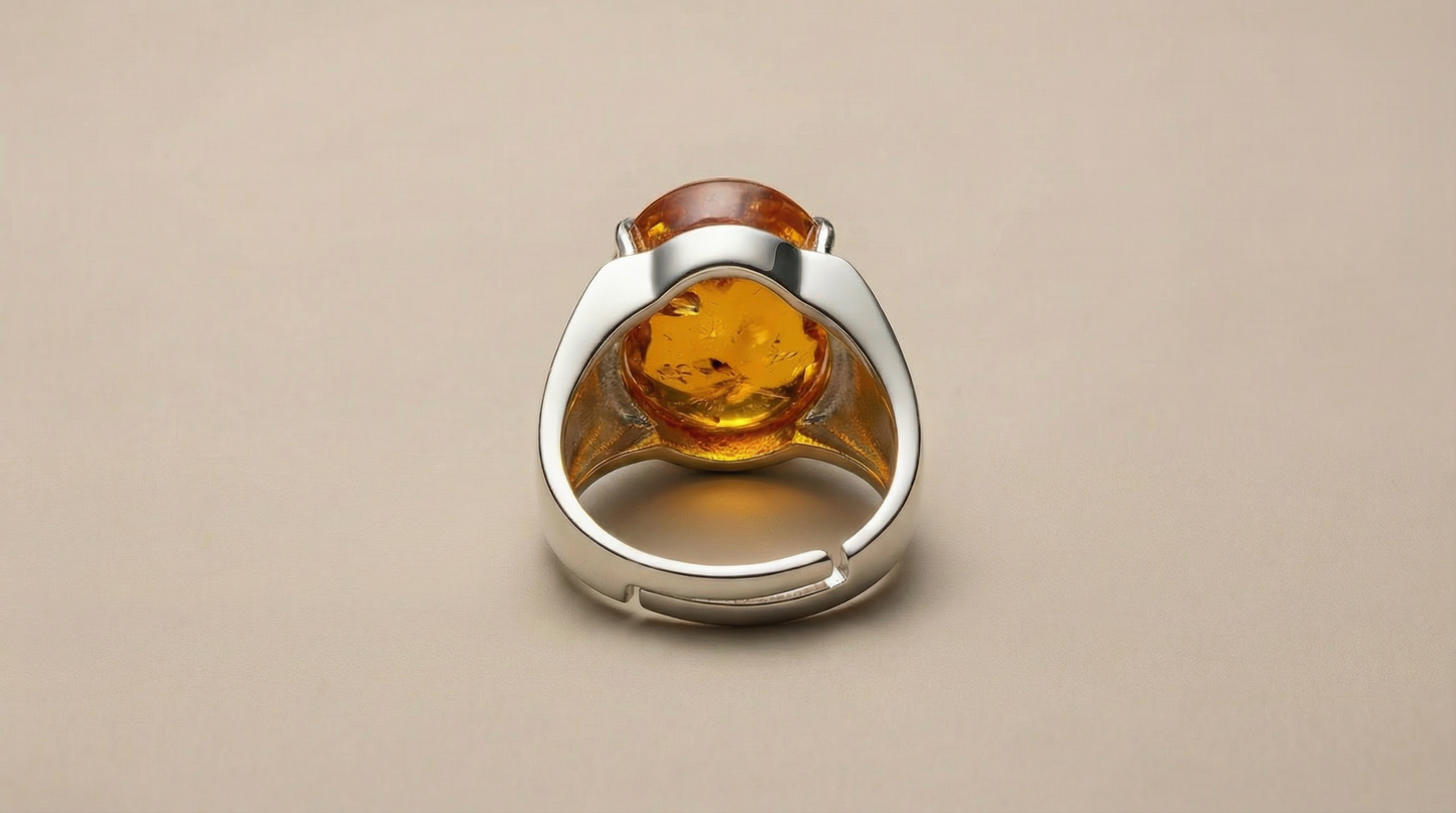 Adjustable silver-tone ring featuring an oval amber cabochon centerpiece with warm honey-gold tones and visible inclusions.