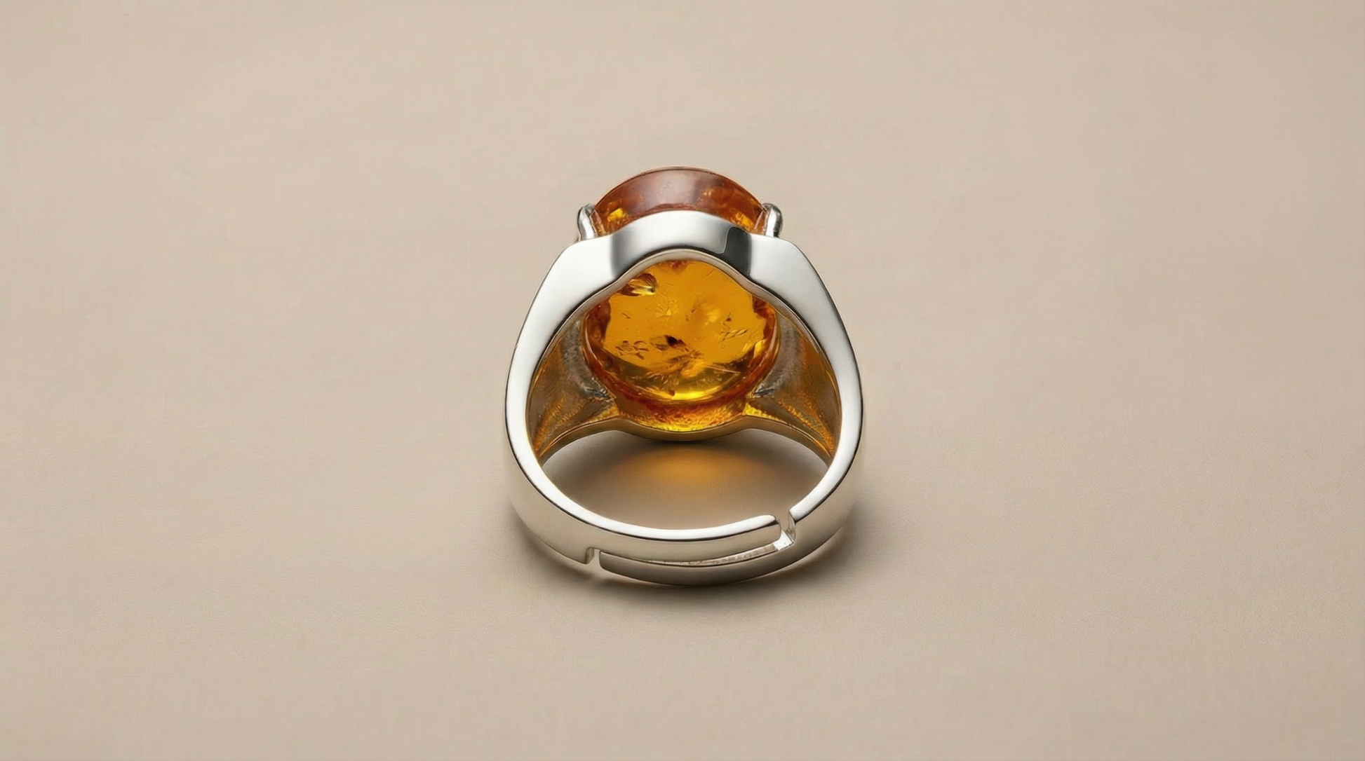 Adjustable silver-tone ring featuring an oval amber cabochon centerpiece with warm honey-gold tones and visible inclusions.