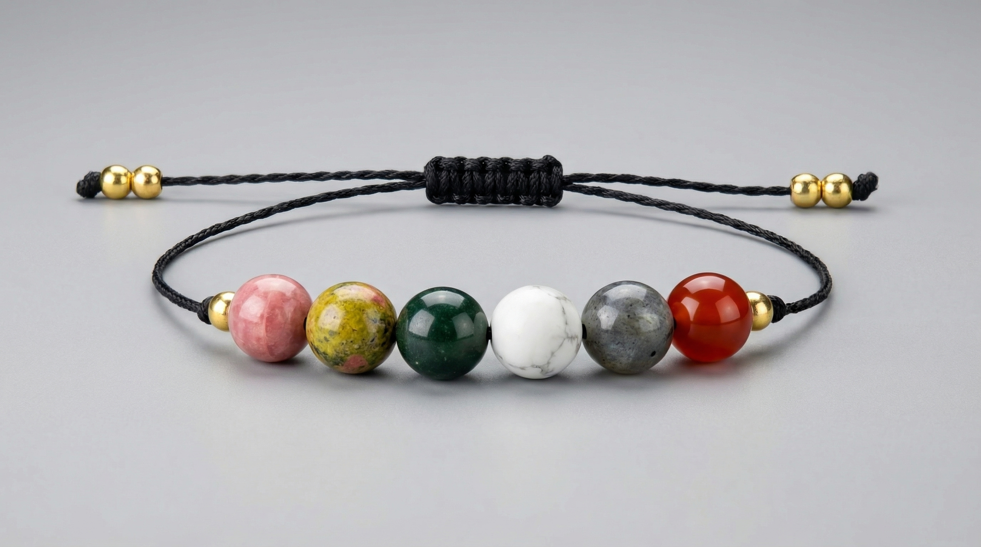 Six-gemstone fertility intention bracelet with Rhodochrosite, Unakite, Merlinite, Moonstone, Black Labradorite and Carnelian on black adjustable cord