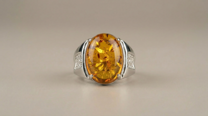 Close-up view of polished adjustable band ring showcasing a large oval amber stone with glowing golden clarity.