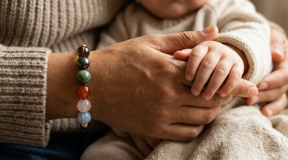 Close-up of a person's hand holding a child's hand, with a colorful beaded bracelet on the wrist. Unisex parenting and caregiver support bracelet with mixed calming and grounding stones